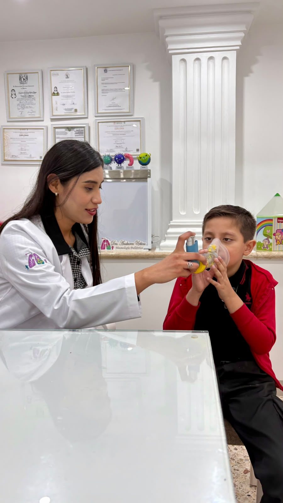 La Dra. Urbina enseña a un niño a usar su inhalador con espaciador